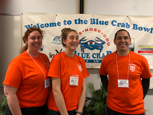 
	Coast Survey employees stand in front of the Blue Crab bowl banner