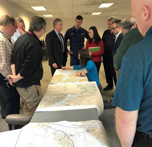 Meeting attendees look over paper nautical charts