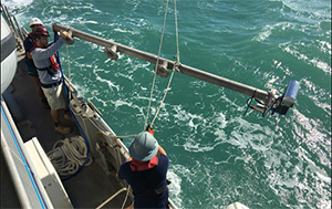 Manta team members lower the multibeam sonar into the water.