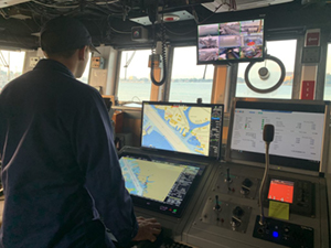 NOAA Corps officer on the bridge of a ship with ENCs displayed.