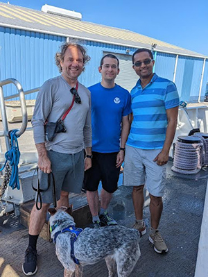 The image here shows Hydrographic Surveys Division Physical Scientists (left to right) Steven Loy, Pearl (Steven's dog), Daniel Garatea and Surafel Abebe are aboard NOAA Ship Thomas Jefferson in Cleveland Ohio.