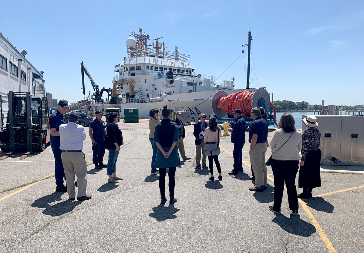 Members of the Marine Board tour the dock at the Atlantic Marine Operations Center as NOAA Ship Henry B. Bigelow sits tied up alongside in the background.