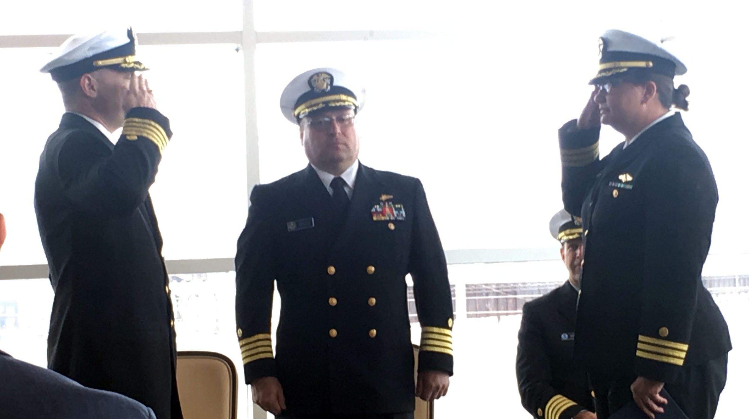 Capt. Chris van Westendorp and Cmdr. Briana Welton Hillstrom salute with Capt. Zezula looking on.