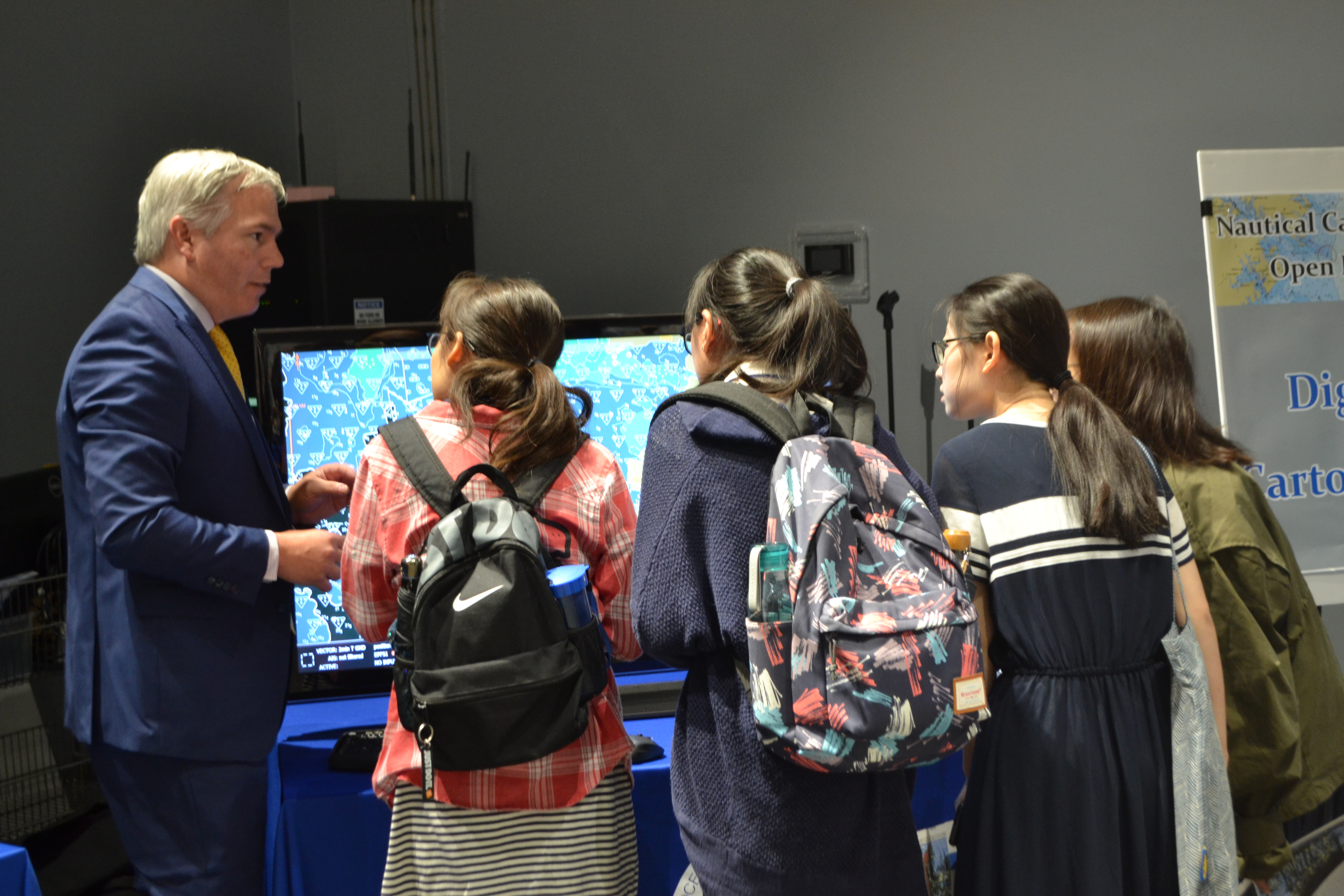 Sean Legeer shows a digital cartography display to visiting students.
