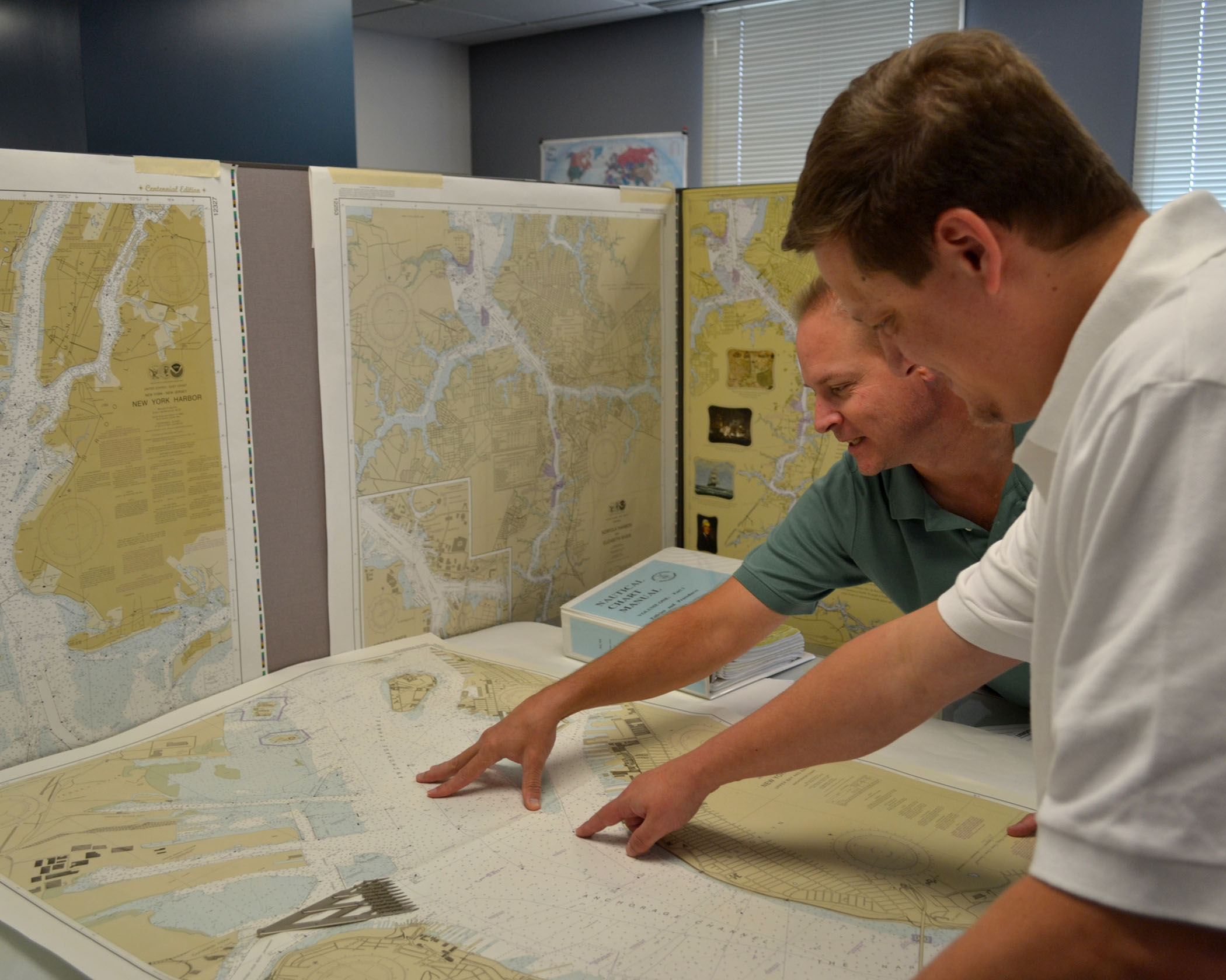 NOAA cartographers review a traditional printed nautical chart.