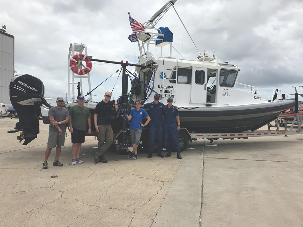 An image showing six hydrographic survey experts standing in front of survey vessel. 