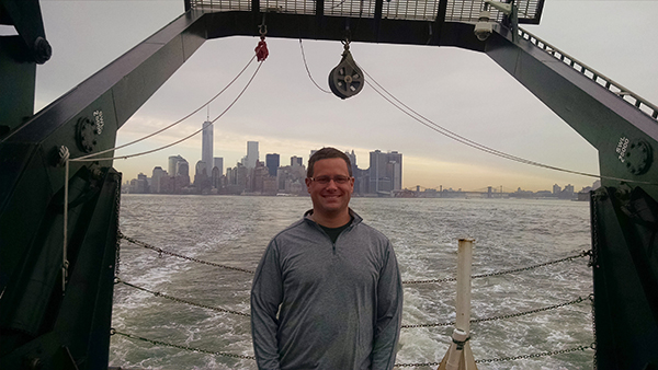 An image of Glen Rice standing on the stern of NOAA Ship Nancy Foster with the skyline of New York city in the background.