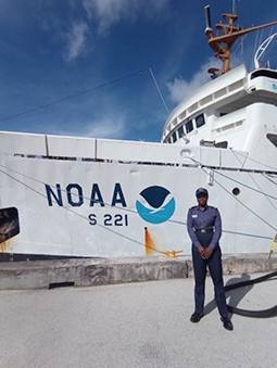 An image showing Sub-Lieutenant Mercy Modupe Ogungbamila standing in front of NOAA Ship Rainier at Victor Pier, Apra Harbor, Guam.