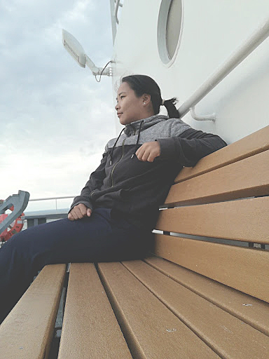 Firosa Tomohamat sitting on a bench on deck 2 of NOAA Ship Thomas Jefferson.