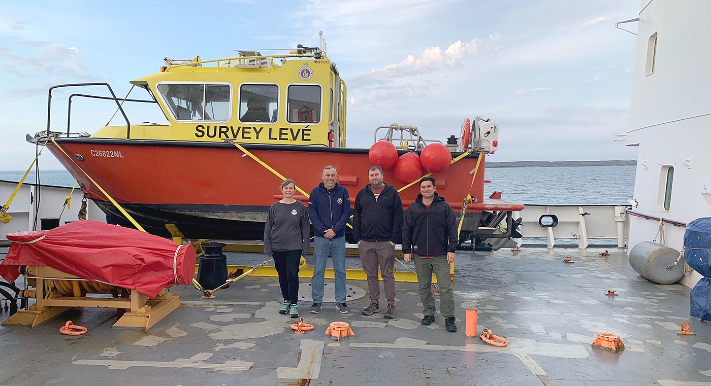 An image of the survey crew standing in front of a survey vessel aboard the deck of the icebreaker .