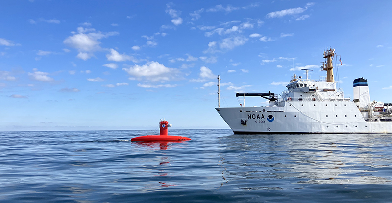An image showing are large white NOAA survey vessel with a smaller red uncrewed survey vessel on the water in Lake Erie.