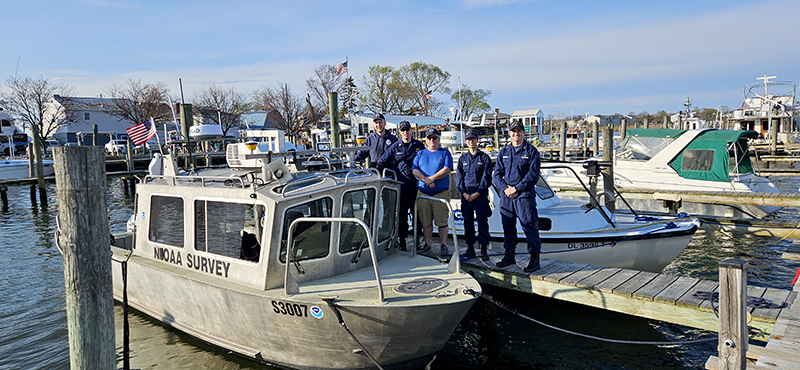 An image of the survey team standing alongside the survey vessel tied up to a dock near the survey area in Baltimore.